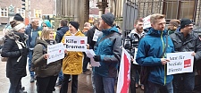 Teilnehmer:innen der Protestaktion mit Pappschildern