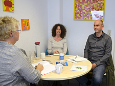 Zwei Frauen und ein Mann am runden Tisch unterhalten sich